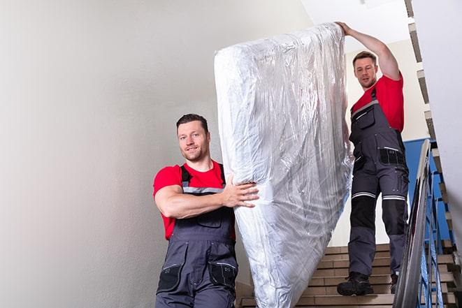 two workers lifting a box spring out of a bedroom in Olivehurst, CA